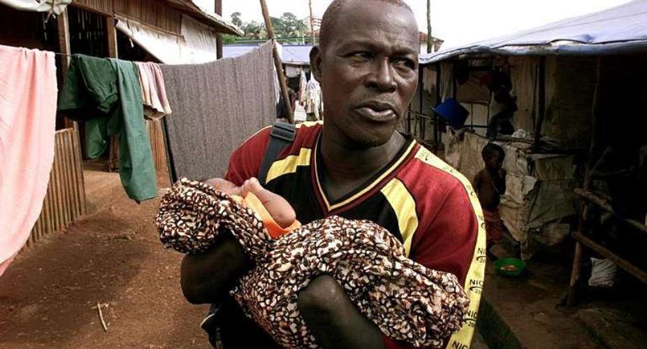 A man who got both hands chopped off during the civil war carries his baby in a special camp for amputees in 2001. By Georges Gobet (AFP/File)