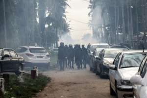 Tension: Riot police walk through a cloud of tear gas after dispersing a crowd of Gbagbo followers. By JOHN WESSELS (AFP)