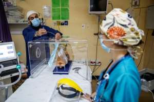 The box aims at preventing health workers from being infected by respiratory droplets -- even ultra-fine particles called aerosols can carry the virus, according to mounting evidence. By Michele Spatari (AFP)