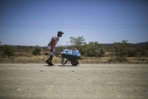 The hot way home: A young man pushes a wheelbarrow with bottles filled with water. By Guillem Sartorio (AFP)