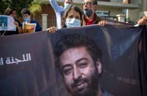 The mother of prominent Moroccan journalist Omar Radi holds up a banner of her son, who is due to hear the verdict of his trial on Monday for espionage and rape, charges he denies.  By FADEL SENNA (AFP)