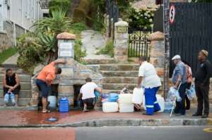 The new normal? People in the Cape Town suburb of St. James queue to collect drinking water from pipes fed by an underground spring