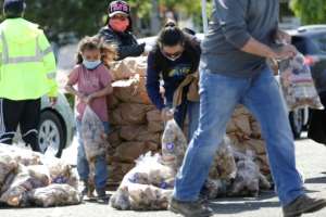 The Reed family in Pasco, Washington, hands out potatoes donated by Washington famers who are giving away a million pounds of excess stock they have as a result of the food service industry slowdown. By Jason Redmond (AFP)