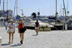 Tourists walk past moored boats at a marina in Tunisia's coastal city of Sousse; despite the crisis, the country remains open to visitors. By Bechir TAIEB (AFP)