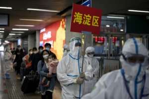 Transport personnel wearing hazmat suits guide travellers arriving from Wuhan to buses, which will take them to their quarantine locations, at Beijing West Railway Station. By Noel CELIS (AFP)