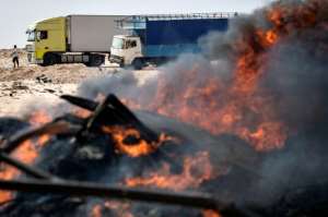 Trucks behind burning waste on a road between Morocco and Mauritania in Guerguerat. By Fadel SENNA (AFP)