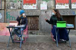 Two 12-year-olds sit in front of Italo Calvino school in Turin as they protest against school closures because of government restrictions over the Covid-19 pandemic. By Miguel MEDINA (AFP)