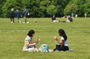 Two women enjoy a drink in the grass in London's Hyde Park, opened for the first time in months. By Glyn KIRK (AFP)