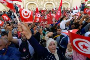 Tunisians raise national flags during a rally against the president along the Habib Bourguiba avenue in the capital Tunis, on October 10. By FETHI BELAID (AFP)