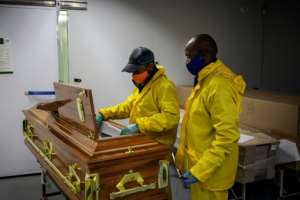 Undertakers clad in masks and protective suits check the coffin containing Motlhabane's remains. By Michele Spatari (AFP)