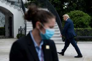 US President Donald Trump walks from Marine One to the White House as a secret service agent wearing a face mask looks in Washington, DC. By Brendan Smialowski (AFP)