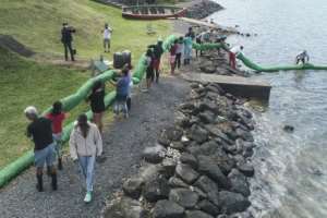 Volunteers carry a handmade oil barrier to block the leaked fuel from the MV Wakashio. By - (L'Express Maurice/AFP)