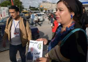 Volunteers distribute photos of Tunisian conservative law professor and presidential candidate Kais Saied, one of two political outsiders in Sunday's election runoff. By FETHI BELAID (AFP)