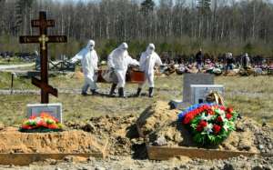 Workers wearing protective gear bury a coronavirus victim at a cemetery on the outskirts of Saint Petersburg. By OLGA MALTSEVA (AFP)