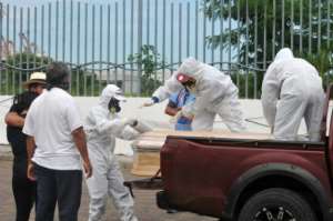 Workers wrap with plastic a coffin with the remains of a person who died from the coronavirus, COVID-19 in Guayaquil, Ecuador. By Jose Sánchez (AFP)