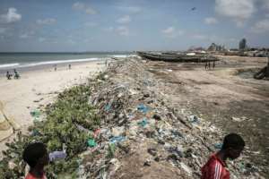 Young Senegalese walk through rubbish piled up along the coastline in Bargny. By JOHN WESSELS (AFP)