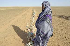 Zghala, a Saharawi woman, looks at Moroccan soldiers in the Al-Mahbes area as she accompanies her 14-year-old son to show him the wall separating the Polisario controlled Western Sahara from Morocco on February 3, 2017