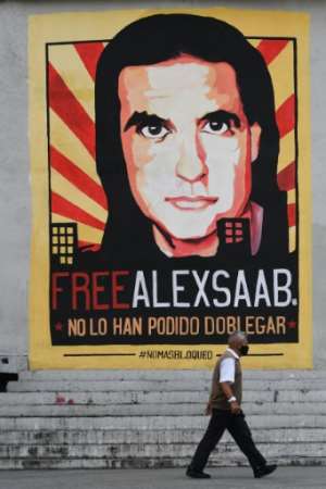 A man walks past a poster demanding the freedom of Colombian businessman Alexander Saab, who was extradited to the United States, in Caracas, on October 17, 2021. By Federico PARRA (AFP)