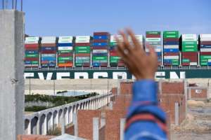 A man waves at the Panama-flagged MV 'Ever Given' container ship as it is tugged in Egypt's Suez Canal after it was fully dislodged from the banks. By Ahmad HASSAN (AFP)