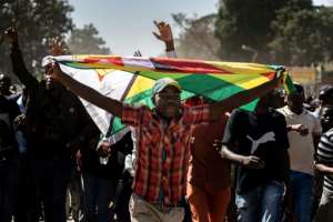 A man clutching the national flag walked with other protesters, demonstrating against the cost of living and lack of essential goods. By Zinyange Auntony (AFP)