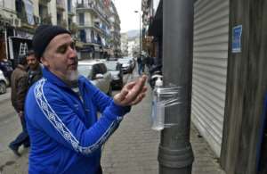 A man disinfects his hands with alcohol gel attached to a pole in Algiers. By RYAD KRAMDI (AFP)
