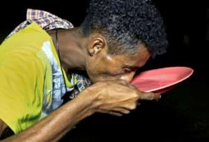 A man drinks water from a plate at the Um Raquba camp in Sudan's eastern Gedaref province. By ASHRAF SHAZLY (AFP/File)