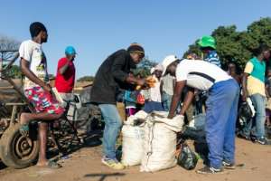 A man hawks carrots to passers-by in the Harare suburb of Mbare. All formal food markets have been closed for three weeks. By Jekesai NJIKIZANA (AFP)