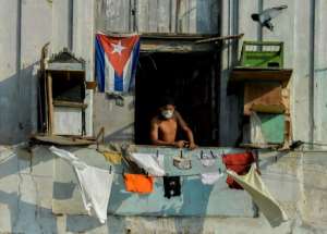 A man in a facemask stands on his balcony in Havana, Cuba. By YAMIL LAGE (AFP)