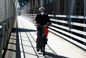 A man rides his bike over the Manhattan Bridge in New York. By Angela Weiss (AFP)