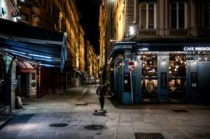 A man rides his skateboard past the deserted Lyon rue Merciere during the first night of curfew. By JEFF PACHOUD (AFP)