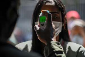 A member of the Bolivarian National Guard checks a woman's temperature outside a market in Caracas, Venezuela on March 20, 2020. By Federico PARRA (AFP)