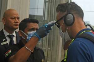 A member of hotel staff wearing a facemask amid concerns over the spread of the COVID-19 novel coronavirus checks the temperature of South African cricket player Faf du Plessis upon his arrival at a hotel in Kolkata. By Dibyangshu SARKAR (AFP)