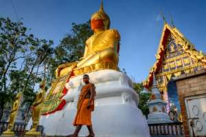 A monk walks in front of a giant Buddha statue wearing a face mask at Wat Nithet Rat Pradit temple in Pathum Thani outside Bangkok. By Mladen ANTONOV (AFP)
