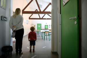 A mother and son stand near glued-on arrows set up to mark social distancing measures at an elementary school a few days before its reopening, in Clairefontaine-en-Yvelines, near Paris. By FRANCK FIFE (AFP)