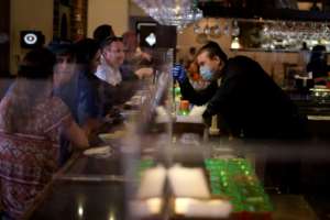 A bartender fist bumps a customer through a plastic barrier at the Picos restaurant in Houston as Texas began lifting stay-at-home orders on May 1. By Mark Felix (AFP)