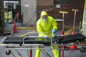 A Belgian firefighter wearing full protective equipment disinfects a stretcher. By Aris Oikonomou (AFP)