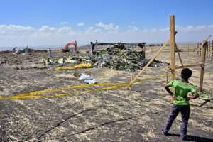 A boy looks on as forensic investigators work at the crash site of an Ethiopian Airlines Boeing 737 MAX aircraft. By TONY KARUMBA (AFP)