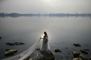 A bride poses for a wedding photographer on East Lake in Wuhan, the city where the virus first emerged in December. By Hector RETAMAL (AFP)