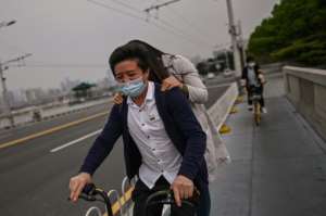 A couple wearing facemasks ride a bicycle over a bridge in Wuhan, where the new coronavirus first appeared in December. By Hector RETAMAL (AFP)