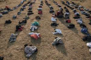 A displaced person sits among piles of clothes being distributed at the camp in Chagni. By EDUARDO SOTERAS (AFP)
