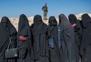 A fighter with the US-backed Syrian Democratic Forces (SDF) keeps watch near women who fled Islamic State group territory in Baghouz. By Fadel SENNA (AFP)