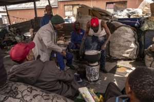 A group of reclaimers -- people who pick up and sell recyclable rubbish -- cook food at the Bekezela slum in Johannesburg. Most people here are depending on food donations to survive during the country's lockdown. By Emmanuel Croset (AFP)
