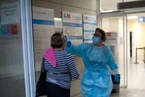A health worker checks the temperature of a woman at the entrance of a health center in Madrid, which announced a partial lockdown for nearly a million people. By OSCAR DEL POZO (AFP)