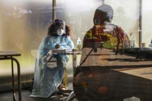 A health worker at Thembisa Hospital, east of Johannesburg, screens visitors for Covid-19 symptoms. By Guillem Sartorio (AFP)