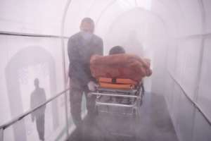 A health worker walks a patient through a disinfection chamber set up in front of a hospital in Mitrovica, Kosovo. By Armend NIMANI (AFP)
