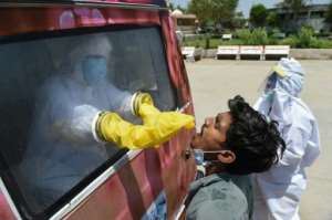 A health official uses a swab to collect a sample from a man for COVID-19 testing at a mobile testing van near Ahmedabad, India. By SAM PANTHAKY (AFP)