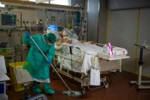 A healthcare worker cleans under the bed of an intensive care coronavirus patient in a hospital in Spain. By MIGUEL RIOPA (AFP)