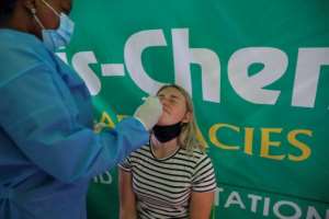A healthcare worker tests a traveller for Covid-19 at Johanessburg airport, just one of the hoops people are having to jump through before they can fly out of South Africa. By Phill Magakoe (AFP)