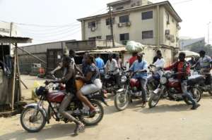 A lady rides on the back of a motorbike taxi in Lagos despite a ban on their use. By PIUS UTOMI EKPEI (AFP)