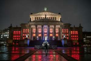 A lone pedestrian walks past the concert hall at Gendarmenmarkt illuminated in red to draw attention to the plight of cultural institutions in Berlin amid the pandemic. By STEFANIE LOOS (AFP)